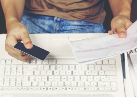 young-man-using-credit-card-paying-bills-laptop